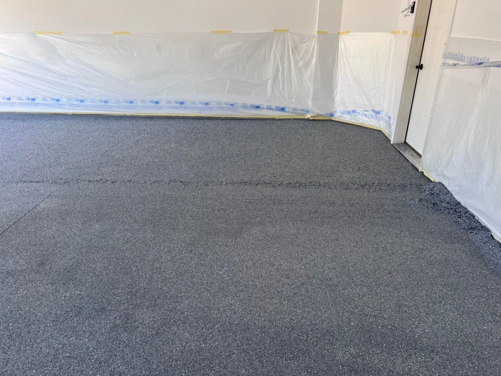 Commercial epoxy floor coating work in Blaine, MN, with wall masking in place