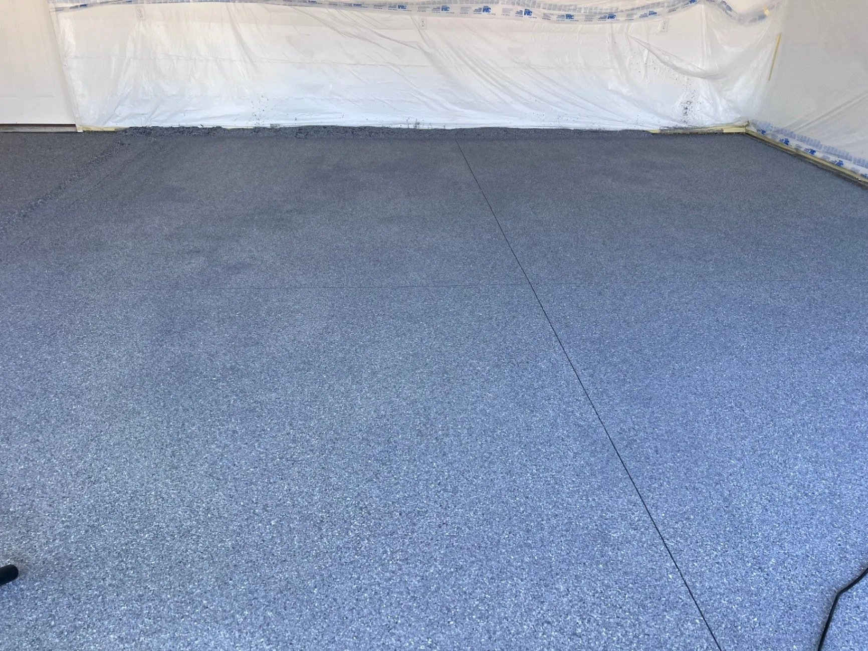 New flake epoxy floor coating in Blaine, MN, with protective plastic along the walls