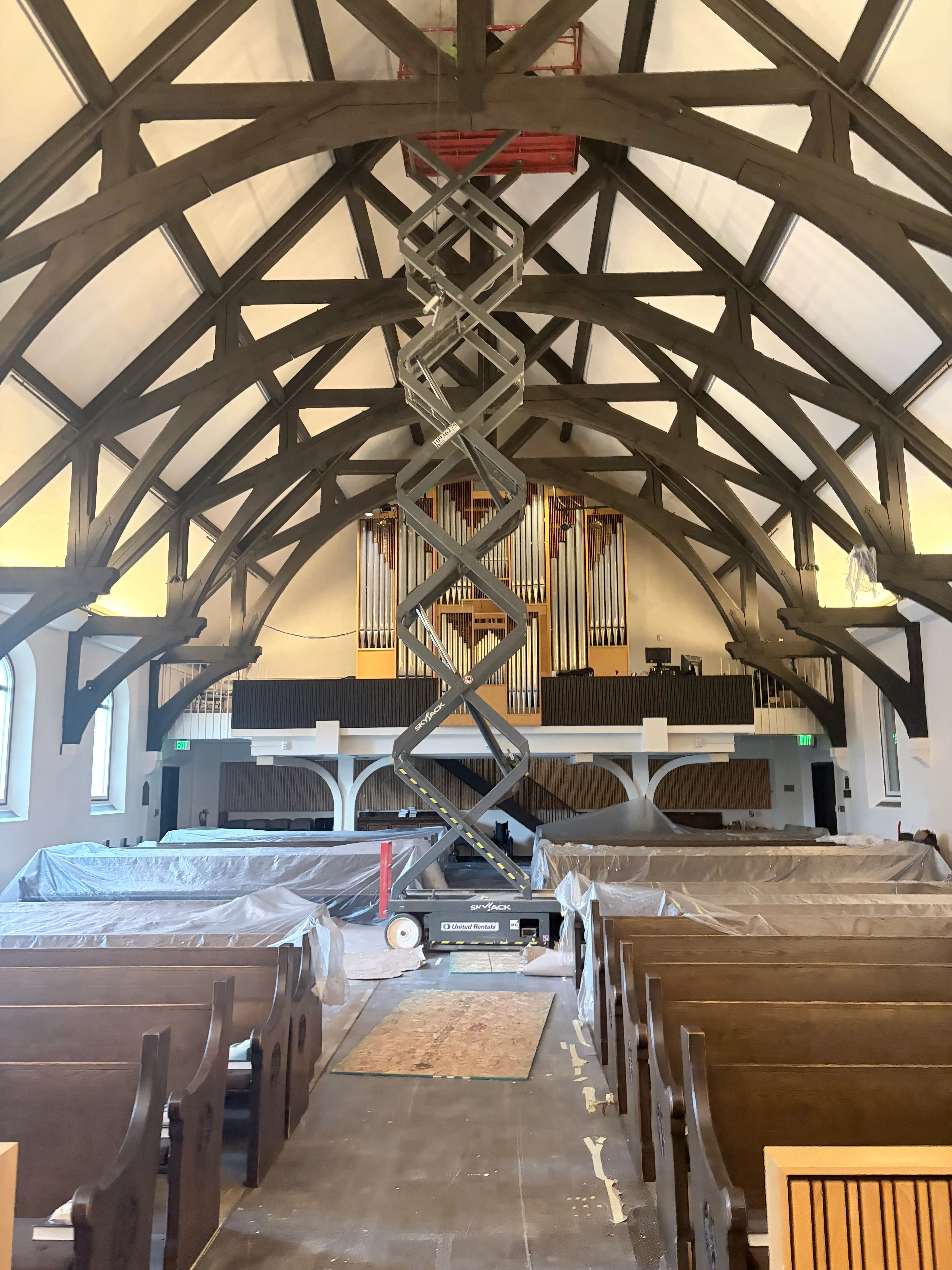 Scissor lift positioned beneath the high ceiling and trusses of a church sanctuary in St. Paul, MN