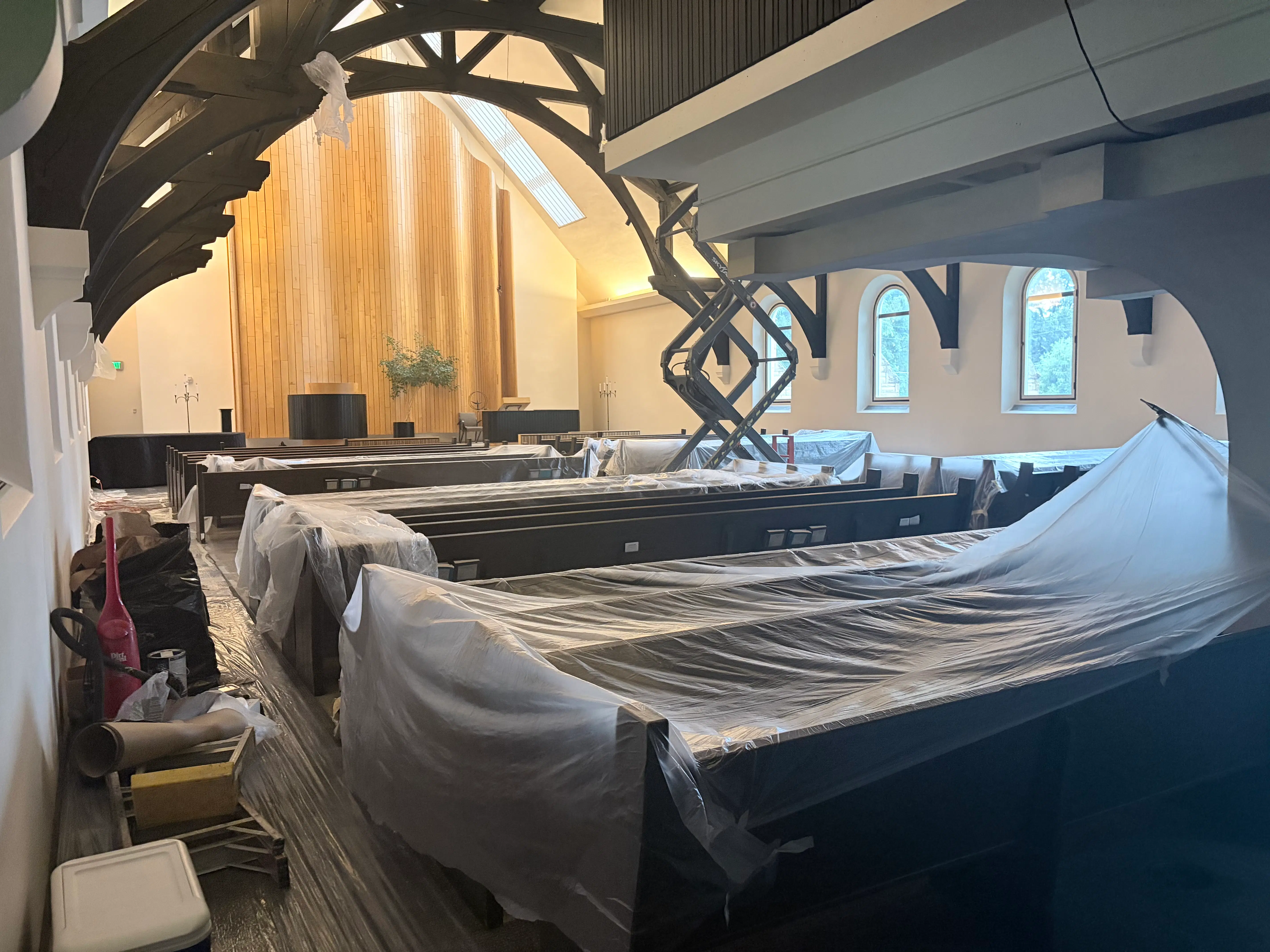 Protected church pews and scissor lift access during sanctuary ceiling painting in St. Paul, MN